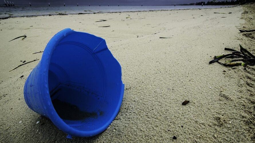 浜辺に転がるプラスチックの青いバケツ